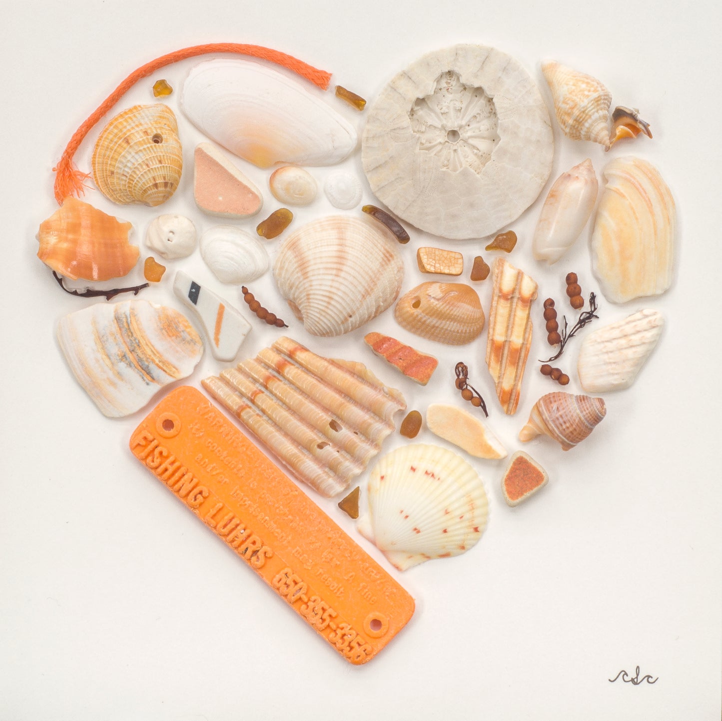 A heart made of orange plastics found on the beach, orange shells, pottery, and algae on a white background